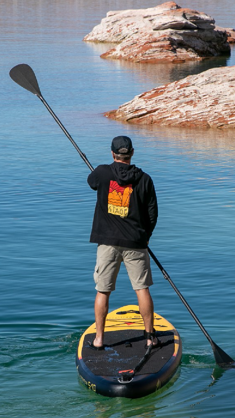A man paddleboarding using a STAGE 2SIDE Double-Sided Paddleboard Paddle and a STAGE S10 Expedition Black and Yellow Inflatable Stand-Up Paddleboard.