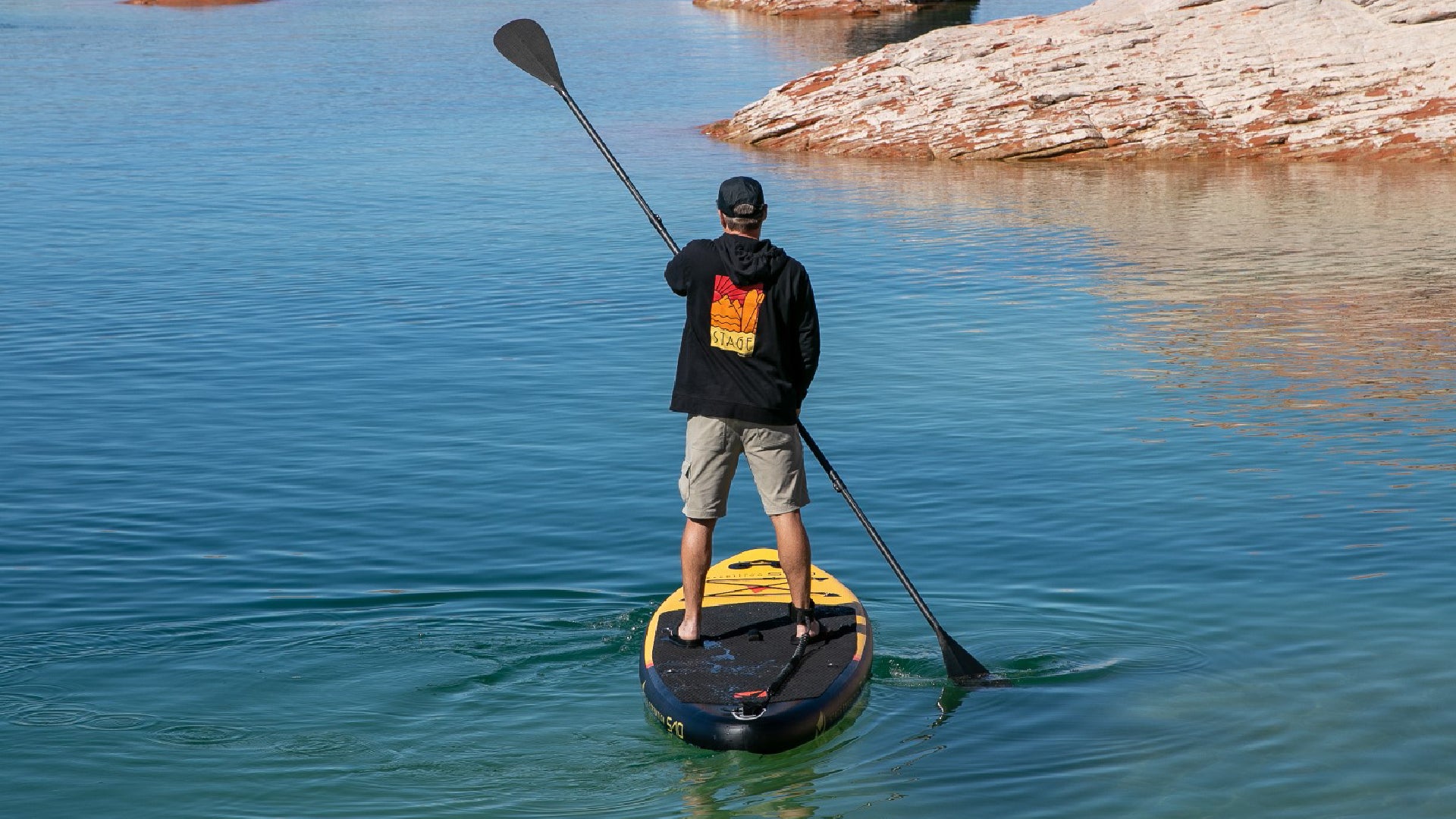 A man paddles using the STAGE 2SIDE Double-Sided Paddleboard Paddle on-top of the STAGE S10 Expedition Inflatable Stand-Up Paddleboard.