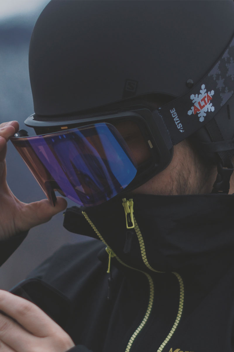 Man changing lenses on his custom STAGE Propnetic magnetic ski goggles featuring an ALTA logo