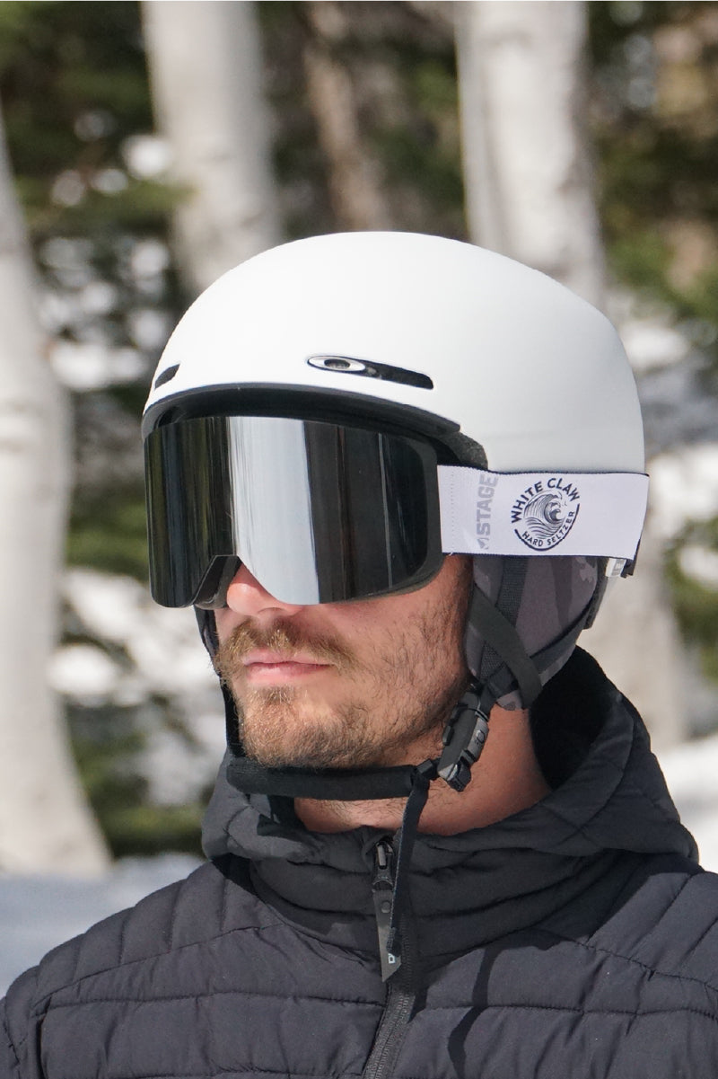 A man wearing custom white ski goggles by STAGE. The custom goggles feature Whiteclaw's logo.