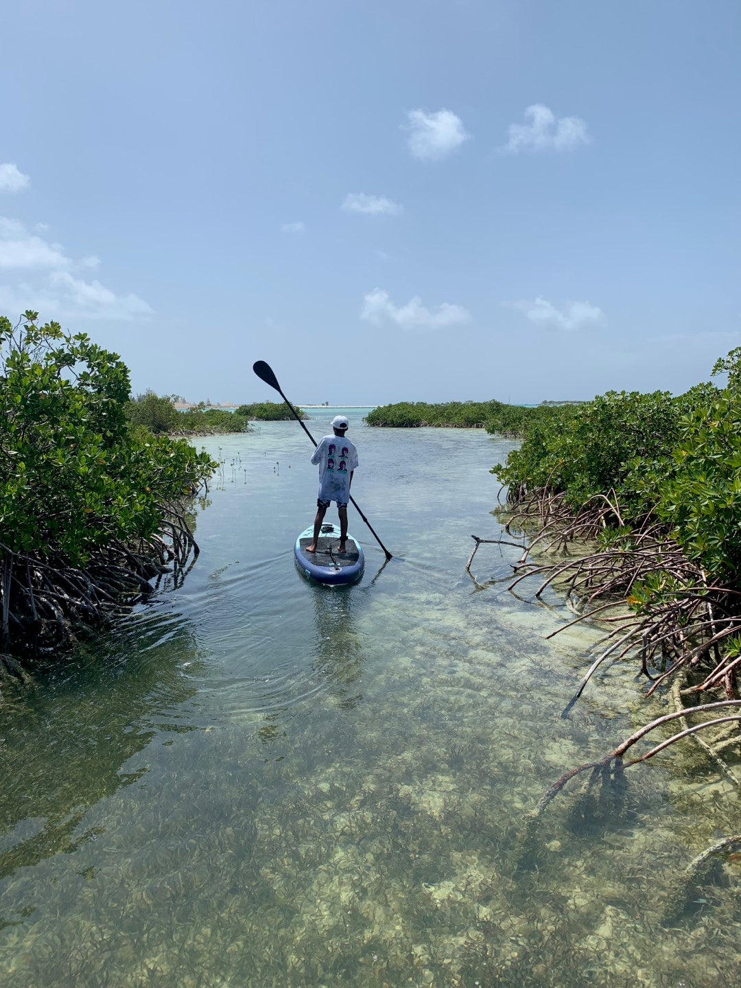 A teenage boy paddles using the STAGE 2SIDE Double Bladed SUP Paddle with a STAGE Inflatable Stand-Up Paddleboard. 