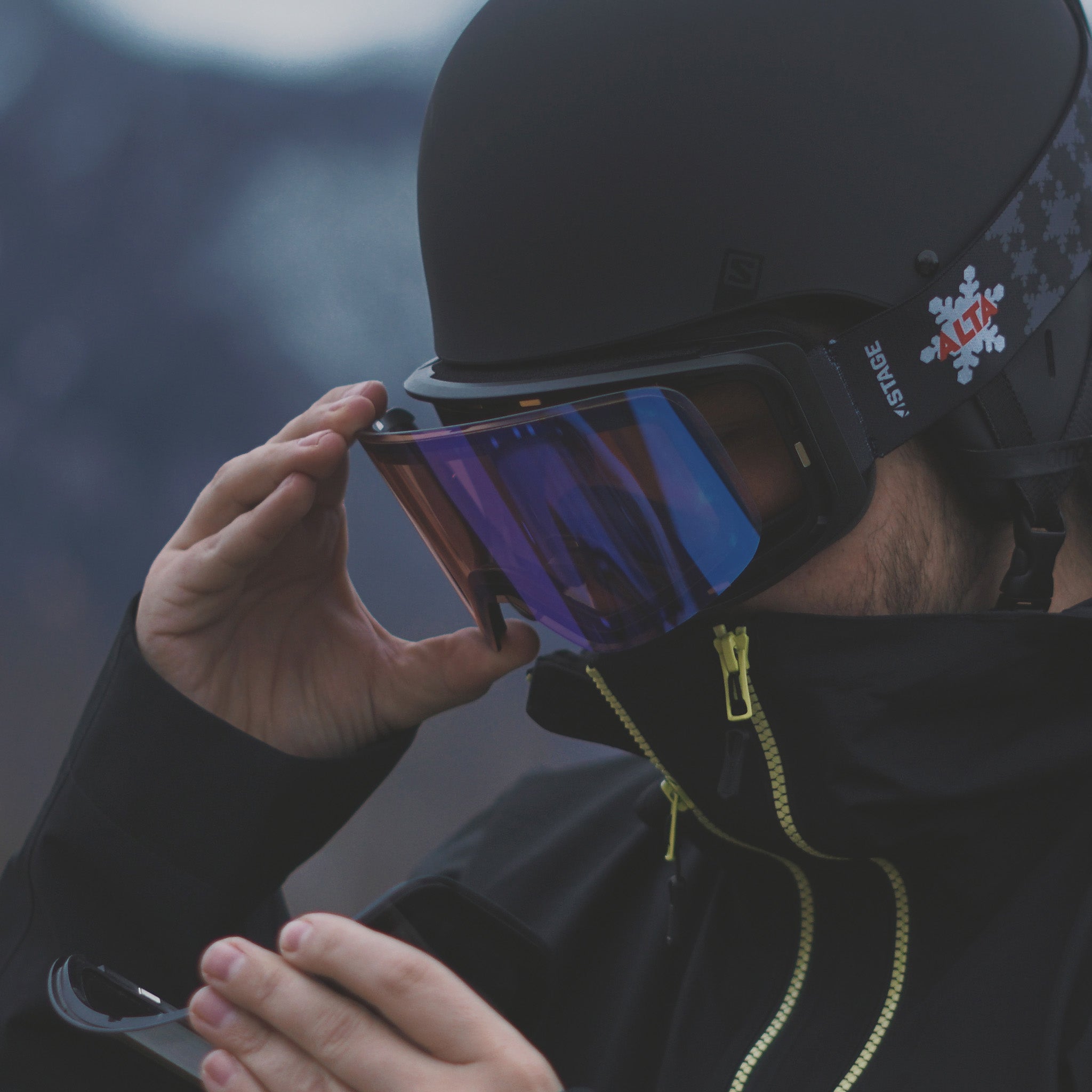 Skier easily swapping lenses on his STAGE Propnetic Magnetic Ski Goggle. The strap featured is the ALTA custom ski goggle strap.
