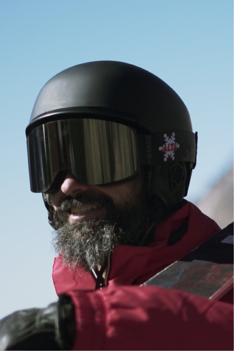 A man wearing custom STAGE Propnetic Ski Goggles with ALTA ski resorts logo. The man is also holding a pair of custom STAGE skis.