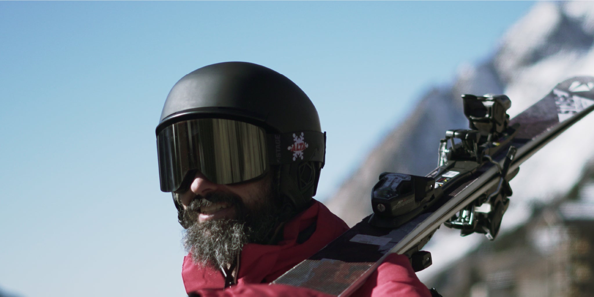 A man wearing custom STAGE Propnetic Ski Goggles with ALTA ski resorts logo. The man is also holding a pair of custom STAGE skis.